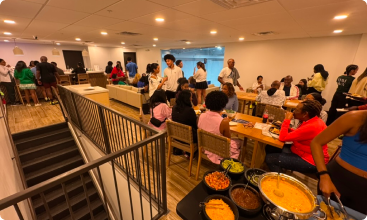 A high-angle view of a crowded, well-lit lounge area where people are socializing and standing by a buffet table.