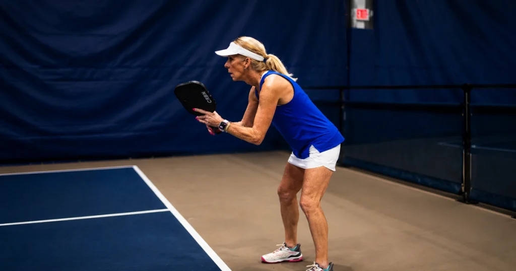 Senior woman preparing to hit the ball during indoor pickleball.