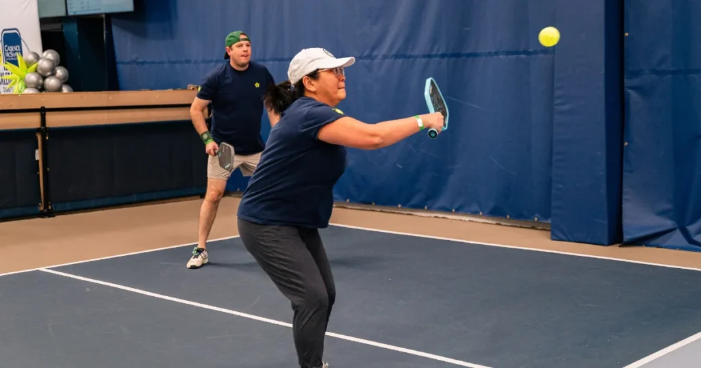 Man and woman playing indoor pickleball